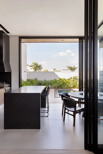 Cocina moderna con isla de piedra y vista a piscina exterior — proyecto Float House, por Daniel Santo