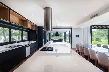 Cocina moderna abierta con isla grande y extractor cilíndrico — proyecto CASA T199, por A'PRIMA - Arquitectura Sustentable, en Los Robles 5901