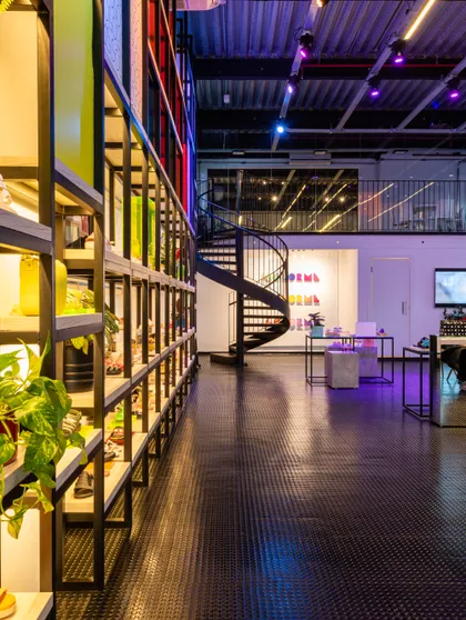 Espacio comercial moderno con escalera espiral, iluminación LED y plantas — proyecto Showroom Melissa, por Pricila Dalzochio