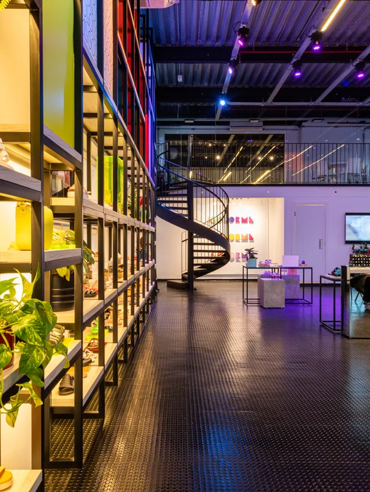 Espacio comercial moderno con escalera espiral, iluminación LED y plantas — proyecto Showroom Melissa, por Pricila Dalzochio