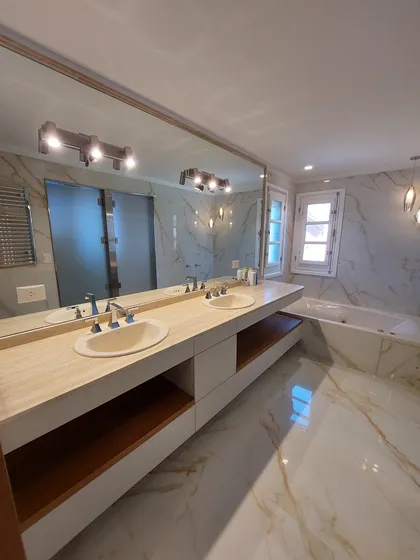 Baño moderno con doble bacha, revestimientos de mármol y bañera exenta — proyecto Reforma Interior - Village, por CM Espacio & Arquitectura, en Pilar