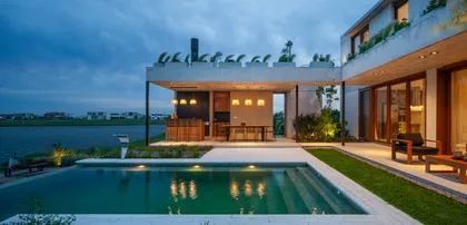 Piscina moderna con área de parrilla y vista al lago al anochecer — proyecto Casa Boating, por LSA. , en Belén de Escobar