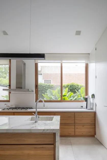 Cocina moderna con isla y vista a jardín exuberante — proyecto CASA OrAz, por Alfredo Orfila arquitectura, en San Isidro