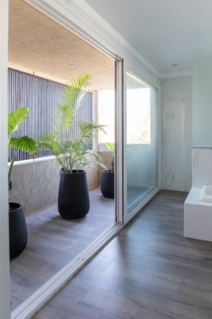 balcón moderno con plantas conecta a baño, puertas de vidrio — proyecto Campo grande IV, por Juarez-Fevre Estudio de Arquitectura , en Buenos Aires