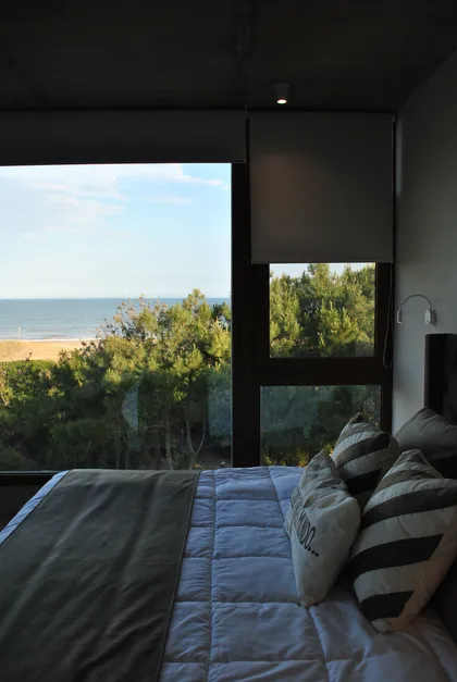 Dormitorio moderno con vista al mar y bosque, grandes ventanales — proyecto Casa FSC, por TAVA Coop, en Pinamar