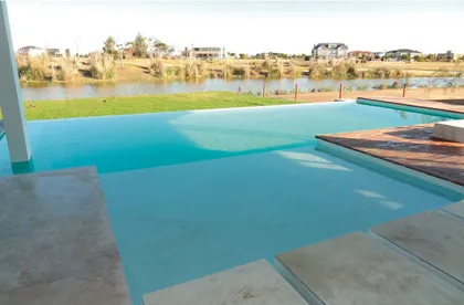 piscina moderna con deck de madera y vista al lago — proyecto CASA GOLF I, por Alejandra Pan Arquitectura, en Nordelta