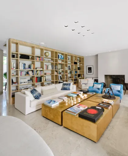 Living moderno con estantería de madera y mesas de centro de bronce — proyecto Casa H, por Estudio Dado, en Belgrano