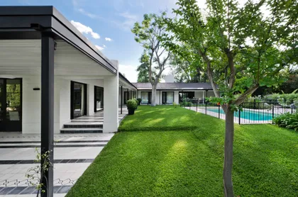fachada moderna con piscina y jardín exuberante — proyecto Casa BA, por Estudio Dado, en Pilar