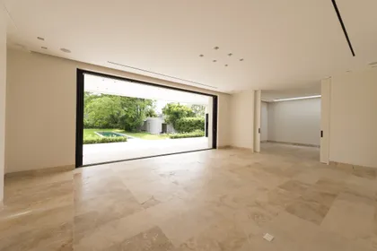Living moderno con ventanales al jardín y piso de travertino — proyecto Casa C, por Estudio Dado, en Belgrano