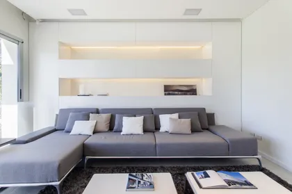Living moderno minimalista con sofá modular y estanterías empotradas — proyecto Modernismo Náutico, por Apaarquitectura, en Tigre