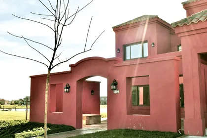 Fachada rosada de casa estilo mediterráneo con arcos y ventanas — proyecto San Marcos 2, por Marconi Silva Arquitectos, en Benavidez