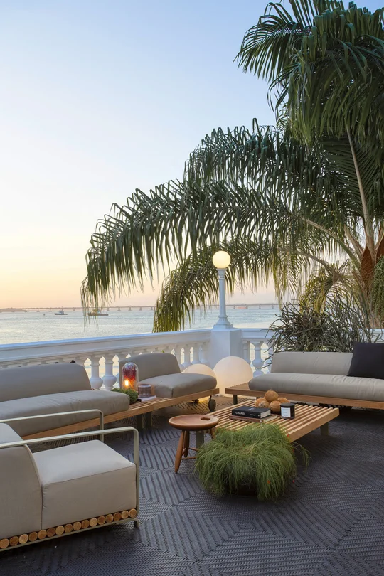Terraza frente al mar con sofás blancos y palmeras al atardecer — proyecto Casa COR 2019, por Studio Ro-ca