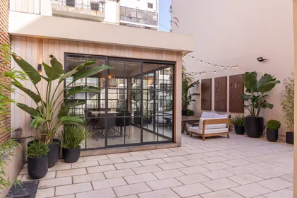 Patio moderno semi-cubierto con sillones blancos y vegetación — proyecto Terraza en la ciudad, por Casa Cunia, en CABA