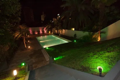 Piscina exterior iluminada de noche con vegetación exuberante — proyecto Detalles, por Geo Estudio, en Buenos Aires