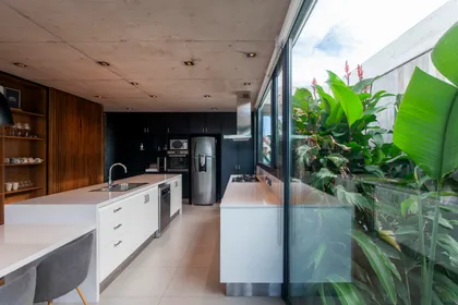 Cocina moderna de plano abierto con isla grande y ventanales — proyecto Casa GUGA, por V2 Arquitectos, en City Bell