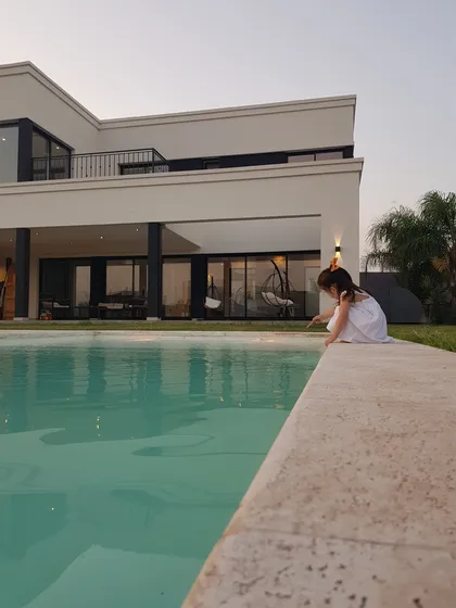 Niña junto a piscina de moderna casa con estilo — proyecto Casa CN451, por EZ architects, en Belén de Escobar