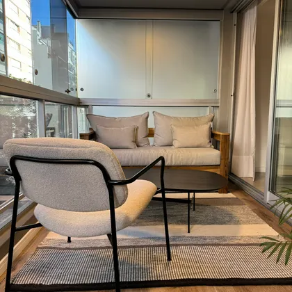 Balcón moderno vidriado con sillones y vista urbana — proyecto Salguero I, por MDBK Arquitectura, en Palermo