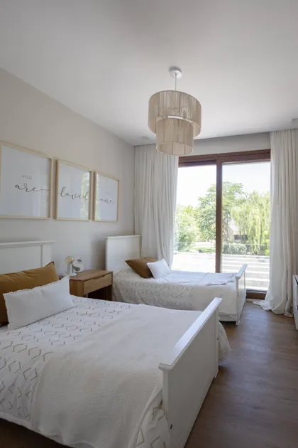 Dormitorio escandinavo con dos camas y vista al exterior — proyecto CASA BaCa, por Alfredo Orfila arquitectura, en Benavidez