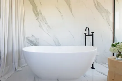 Baño moderno con bañera exenta blanca sobre pared de mármol — proyecto Santa Maria De Tigre, por Parq Estudio, en Tigre