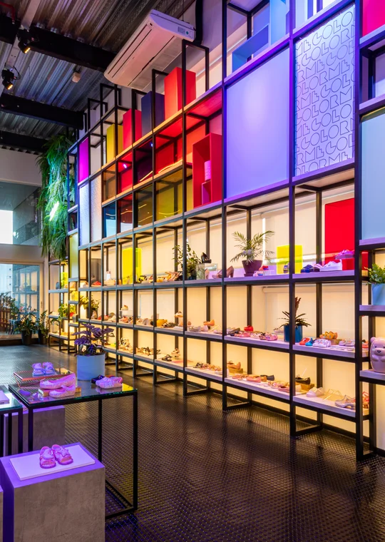 Vidriera comercial con estanterías iluminadas en colores neón vibrantes — proyecto Showroom Melissa, por Pricila Dalzochio
