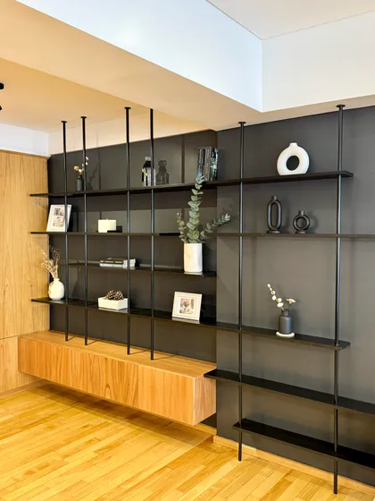 Living moderno con estantería modular negra y mueble flotante de madera — proyecto Mendoza, por MDBK Arquitectura, en Belgrano