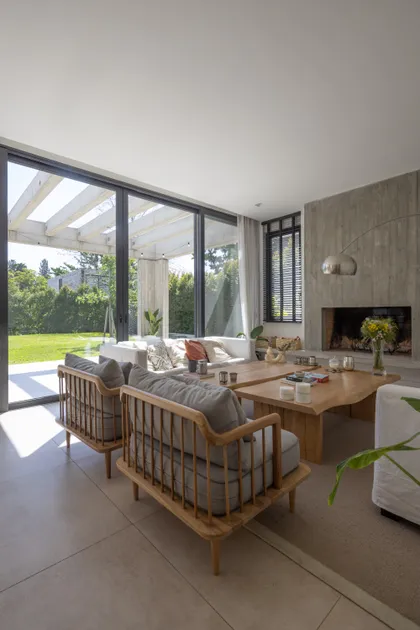 Living moderno con ventanales, chimenea de hormigón y mesa de madera — proyecto CASA RuZa, por Alfredo Orfila arquitectura, en Benavidez
