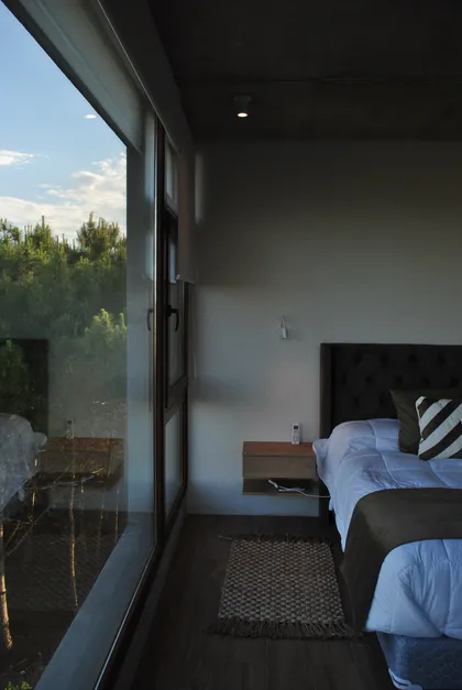 dormitorio moderno con vista al bosque y ventana de piso a techo — proyecto Casa FSC, por TAVA Coop, en Pinamar