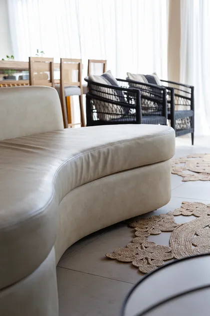 Sofá curvo beige de cuero, sillones de ratán y alfombras de yute — proyecto Casa Canning, por Gaby Alfonso, en Canning