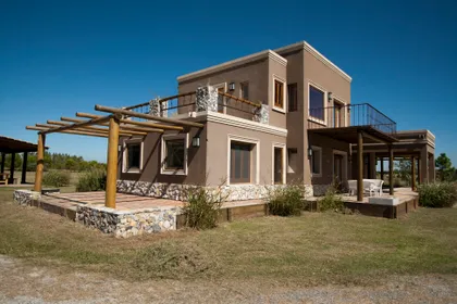 Casa moderna con fachada de estuco y pérgola de madera — proyecto  Inmuebles, por Geo Estudio, en Buenos Aires