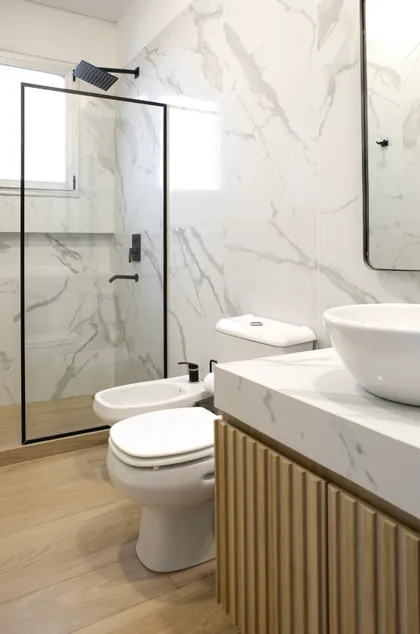 Baño moderno con mármol, madera y grifería negra — proyecto Obra El Encuentro, por Arq. Lourdes Yarade Saravia, en Benavidez