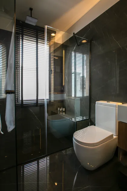 Baño moderno con paredes de mármol gris, suelo negro y ducha de cristal — proyecto Obra Newman M, por Arq. Lourdes Yarade Saravia, en Benavidez