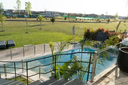 Piscina moderna con deck de piedra y reposeras blancas — proyecto Casa Pomelo, por FeelX Tecnología SRL, en Canning