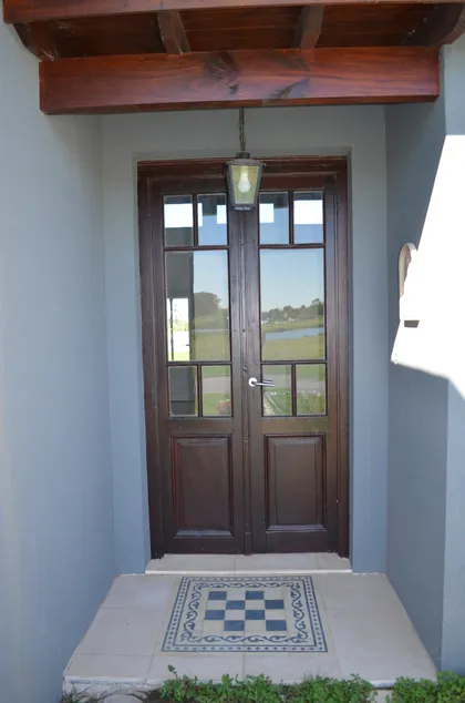 Puerta doble de madera oscura con vigas expuestas — proyecto San Matías, por GeN Arquitectura, en Ingeniero Maschwitz