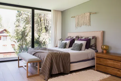 Dormitorio luminoso con vista al bosque y detalles boho — proyecto Casa Highland Park, por C - ESTUDIO, en Pilar