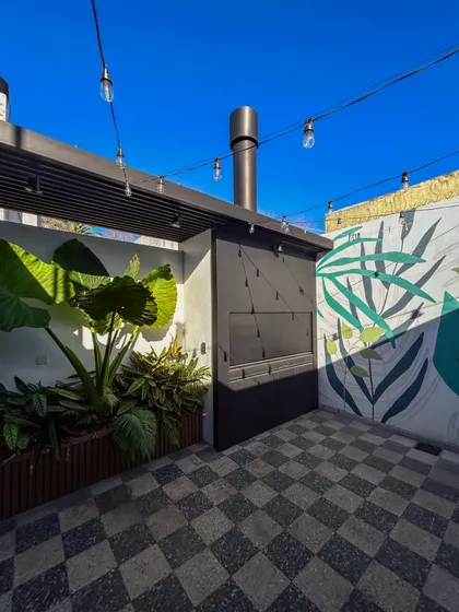 Patio moderno con piso damero, parrilla y luces colgantes — proyecto Vivienda Mari y Lean, por Jeitinho Estudió Creativo, en La Plata