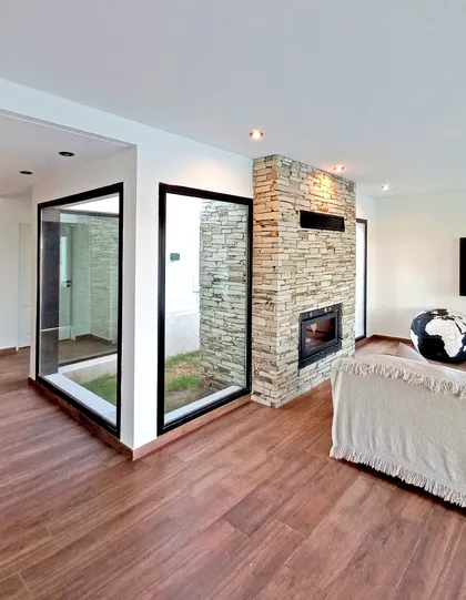 Living moderno con chimenea de piedra y patio interior — proyecto Casa CN451, por EZ architects, en Belén de Escobar