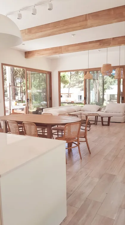 Living comedor moderno rústico con vigas de madera y grandes ventanales — proyecto Casa NF, por TAVA Coop, en Pinamar