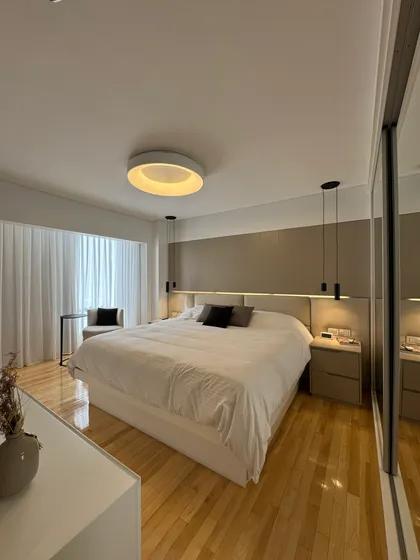 Dormitorio moderno con cama grande, luz cálida y suelo de madera — proyecto Mendoza, por MDBK Arquitectura, en Belgrano