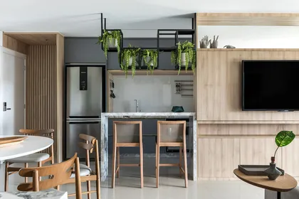 Cocina abierta moderna con isla de madera, plantas colgantes y electrodomésticos de acero — proyecto Apartamento MV, por GabrielaCasagrande Arquitetura