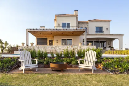Fachada de casa mediterránea con pérgola y área de fogata — proyecto Casa MF, por Estudio Junor, en Belén de Escobar