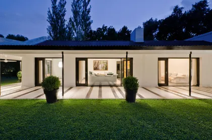 Fachada moderna con iluminación nocturna y pérgola — proyecto Casa BA, por Estudio Dado, en Pilar