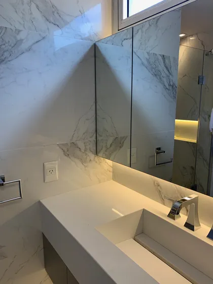Baño moderno con revestimiento de mármol, bacha integrada y grifería angular — proyecto Piso en Nuñez, por Gutman+Lehrer Arquitectas, en Núñez