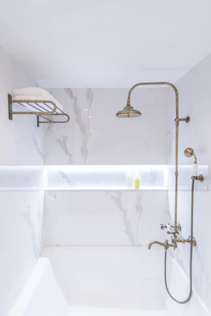 baño clásico con ducha de latón y bañera blanca — proyecto Arce 943, por ST Arquitectas, en CABA