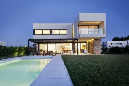 Fachada de casa moderna blanca con pileta, jardín y ventanas de piso a techo — proyecto CASA A, por GMARQ