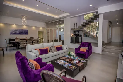 Living moderno con escalera flotante y sillones morados — proyecto Vivienda Unifamiliar en Pinamar, por Estudio Schifano, en Pinamar