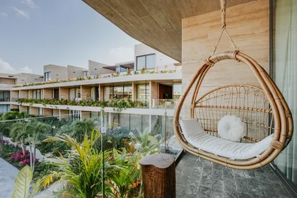 Balcón moderno con silla colgante de ratán y vista costera — proyecto Contemporary Modern Living, por Interiors Tulum
