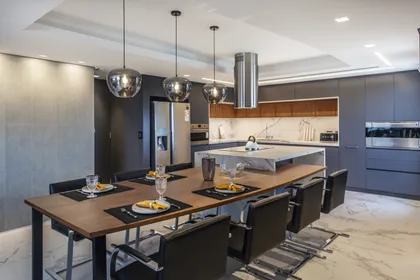 Cocina moderna de planta abierta con isla y luces colgantes — proyecto Pacífico BRT, por Vanguarda Arquitectos, en CABA