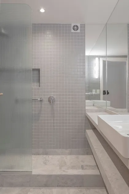 Baño moderno con ducha y vanitory flotante de mármol — proyecto Reforma O'Higgins, por Estudio YME, en Belgrano