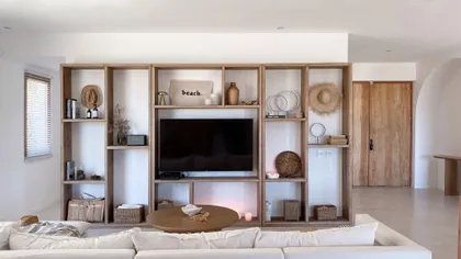 Sala de estar boho escandinava con estanterías de madera integradas — proyecto El Refugio, por Grupo Pauta Arquitectura, en Pinamar