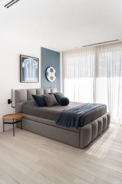 Dormitorio moderno con temática de fútbol, cama gris y cortinas blancas — proyecto PROYECTO NAUDIR II, por July Acosta Home, en Belén de Escobar